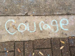 the word courage written on the sidewalk