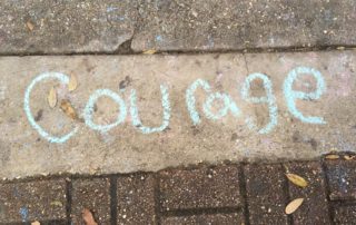 the word courage written on the sidewalk