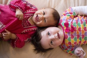 two babies on a bed laughing