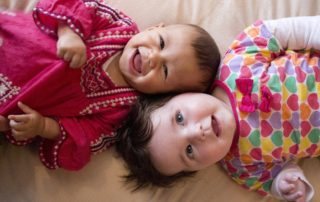 two babies on a bed laughing