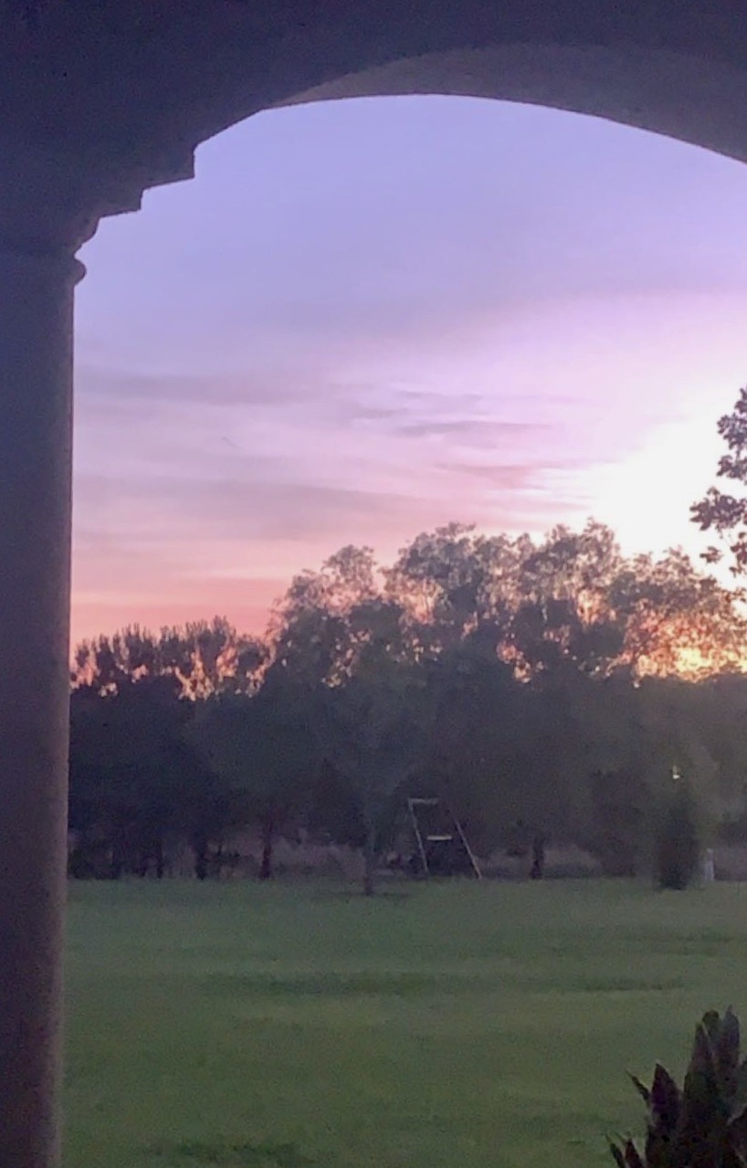 sunset through arches with a swing and tress in the background