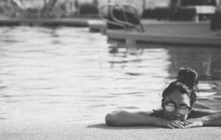 girl looking over the edge of a pool wearing sunglasses-live life to the fullest