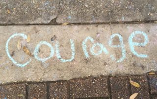 the word courage written in blue on a sidewalk-daring leadership