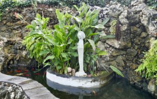 a courtyard with a koi pond and a statue of the madonna-becoming more you