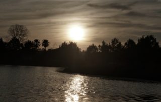 the setting sun casts a glowing reflection on a lake in sepia-a backdrop for a poem