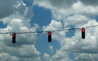 three red stop lights against a blue sky with white clouds reminding us to stop setting goals if we don't try three things
