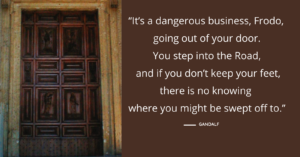 a tall brown door and a quotation to the right from J.R.R. Tolkien about stepping pout your door