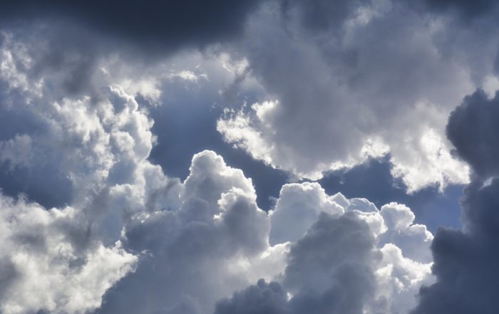 The blue sky peaks through fluffy white clouds surrounded by dark storm clouds