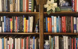 A bookshelf with books, vases, and a silk magnolia blossom-the start of a book list