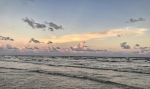 waves rolling onto the shore at sunset with pink and grey clouds against a blue sky-healing powers of the ocean