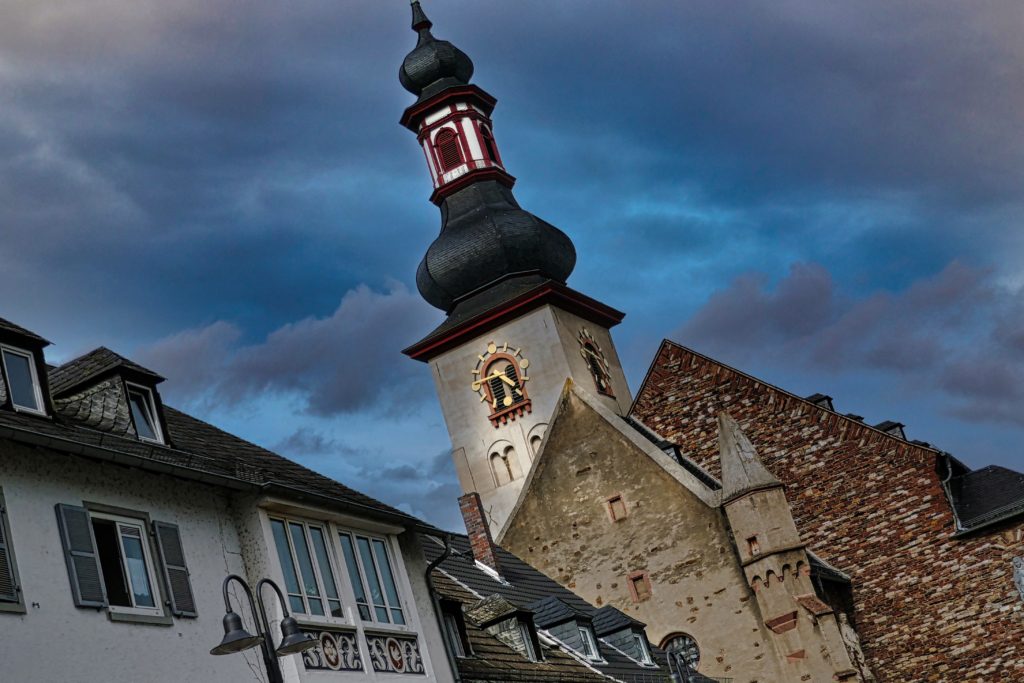 a clock marks the time on a church steeple with the clouds of a setting sun in the background as I thought I was too old