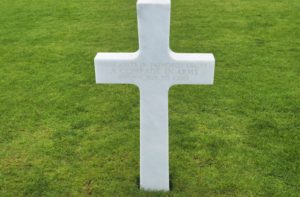 a single white cross against the green grass at the Luxembourg American Cemetery