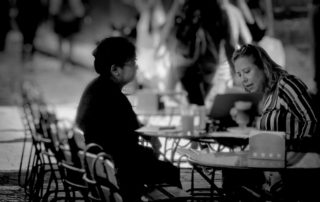 black and white photo of two women sitting at a cafe table talking