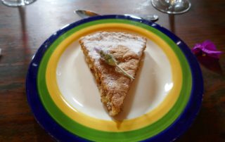 A slice of apple pie on a white saucer rimmed in yellow, green , and blue