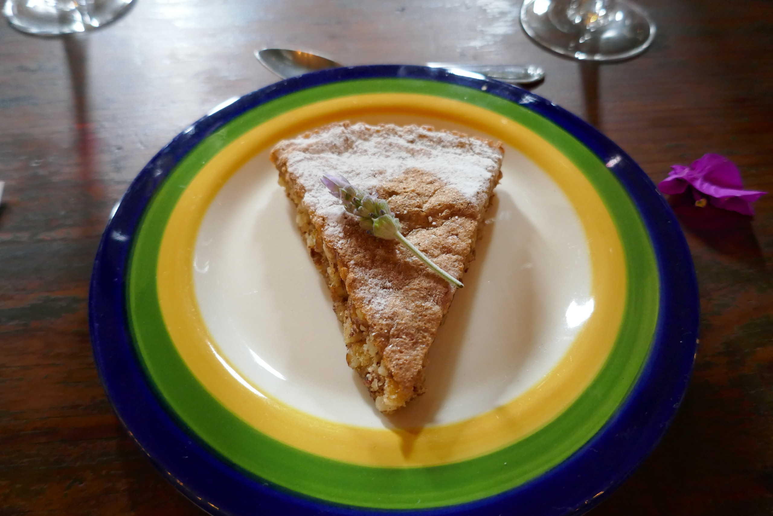 A slice of apple pie on a white saucer rimmed in yellow, green , and blue