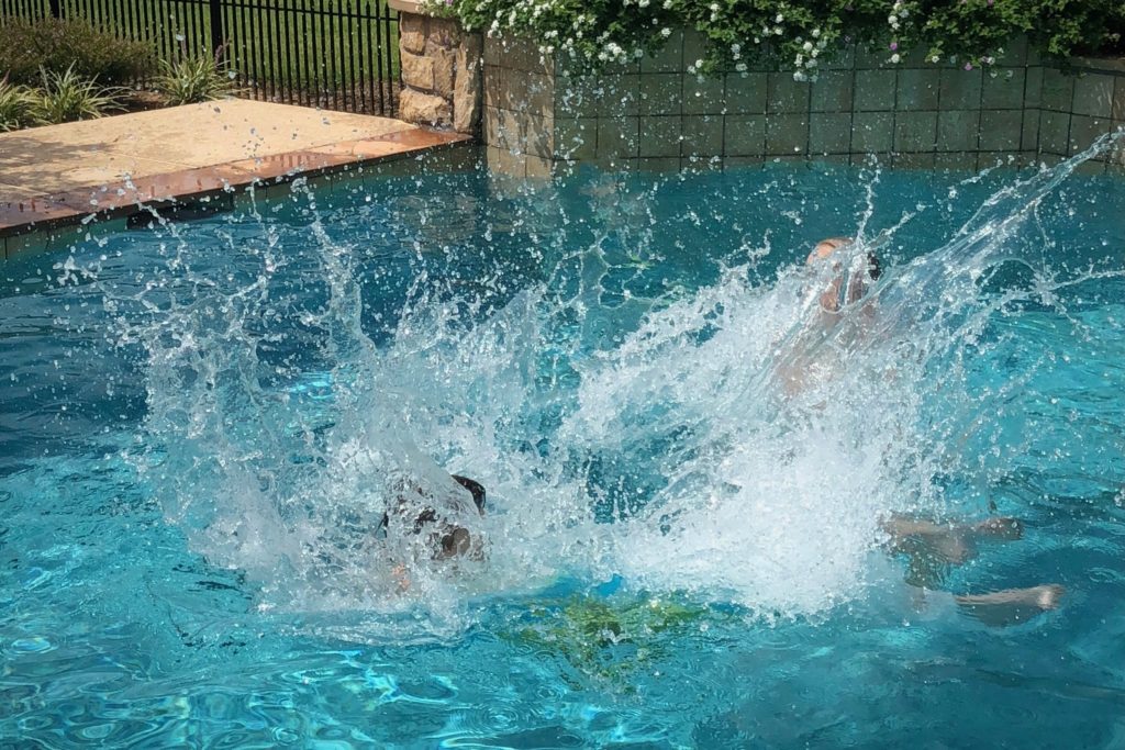 A Big Splash © Kathryn LeRoy: Two children create a big splash while jumping into a bright blue swimming pool on a sunny day.