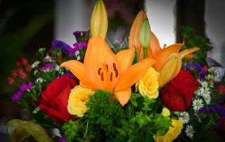 Birthday Bouquet © Kathryn LeRoyA vibrant bouquet featuring orange lilies, red roses, yellow blooms, and purple flowers amidst lush greenery.