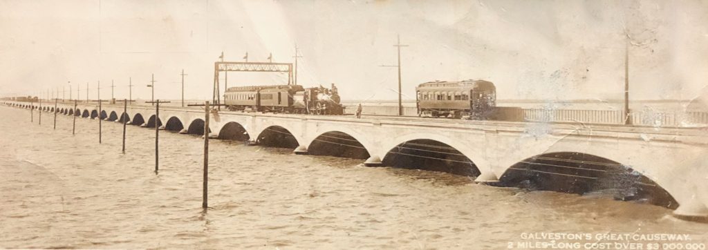 Historic image of Galveston's Great Causeway, featuring a train and multiple arched bridges over the water, showcasing early 20th-century architecture.