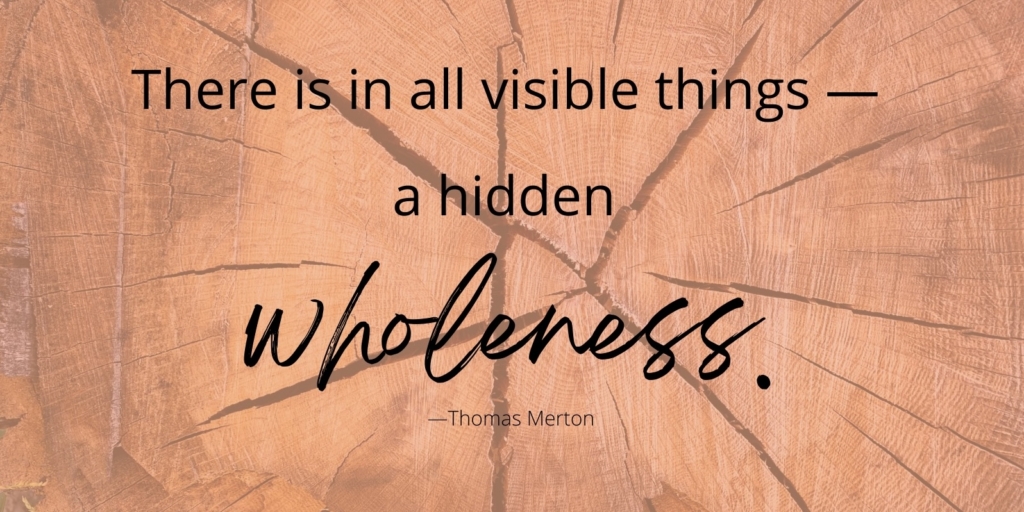Inspirational quote over a warm wood-grain background: “There is in all visible things—a hidden wholeness.” — Thomas Merton.