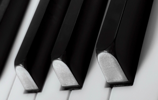 Black-and-white close-up of several angled piano keys, emphasizing alternating dark and light keys.